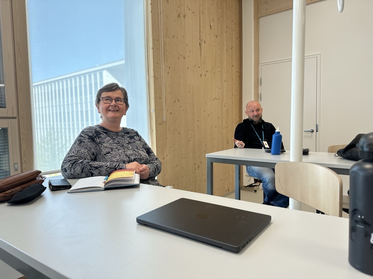 picture of a woman and a man sitting in a classroom, smiling and talking to someone out of frame