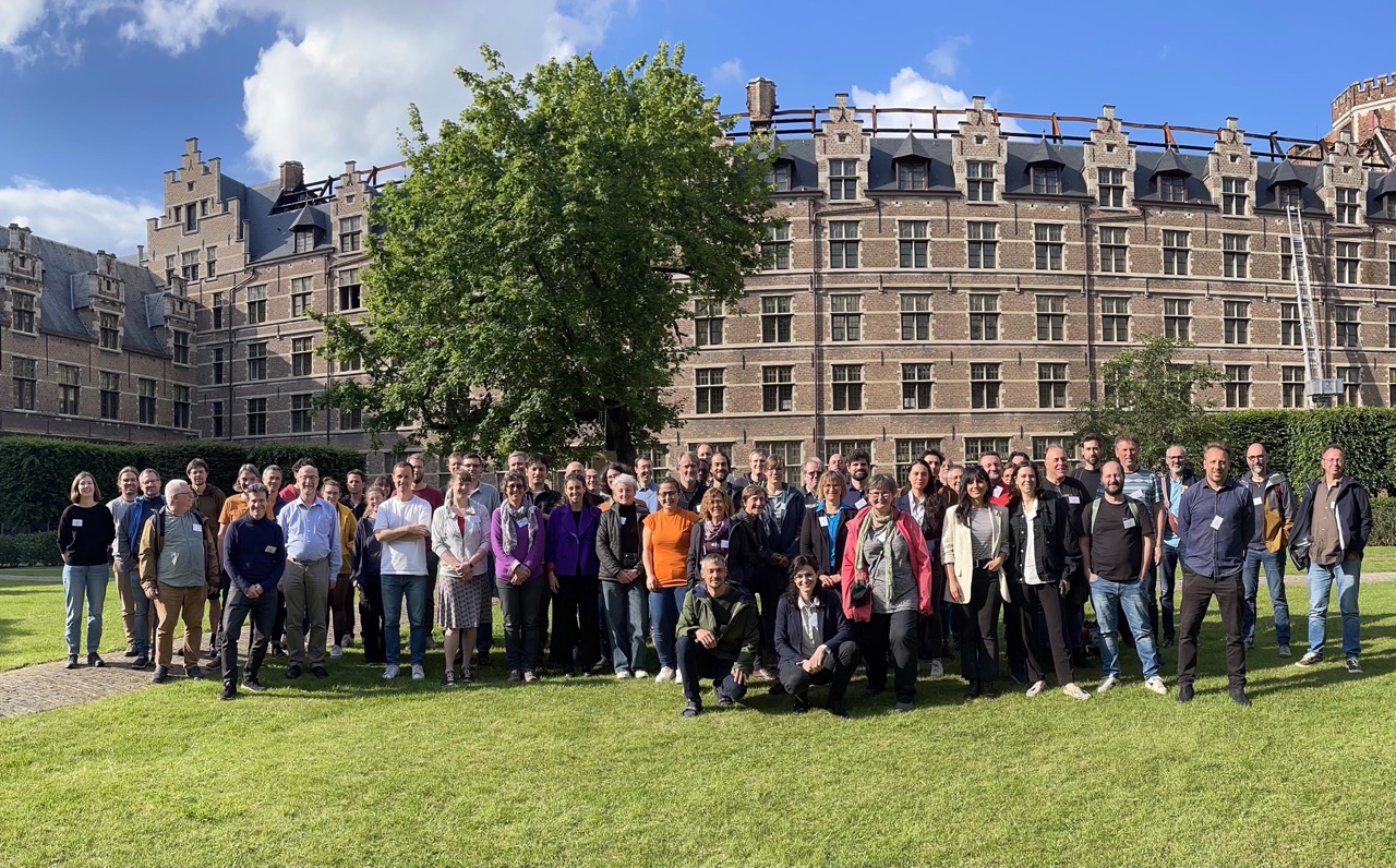 a group picture of scientists smiling in front of an university building