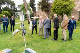 group of people standing around an eddycovariance instrument on green grass 