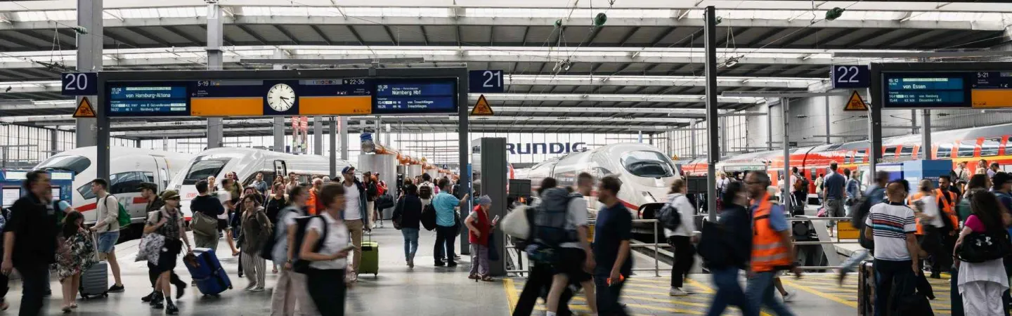 busy train station with trains on the platform and crowds of people around