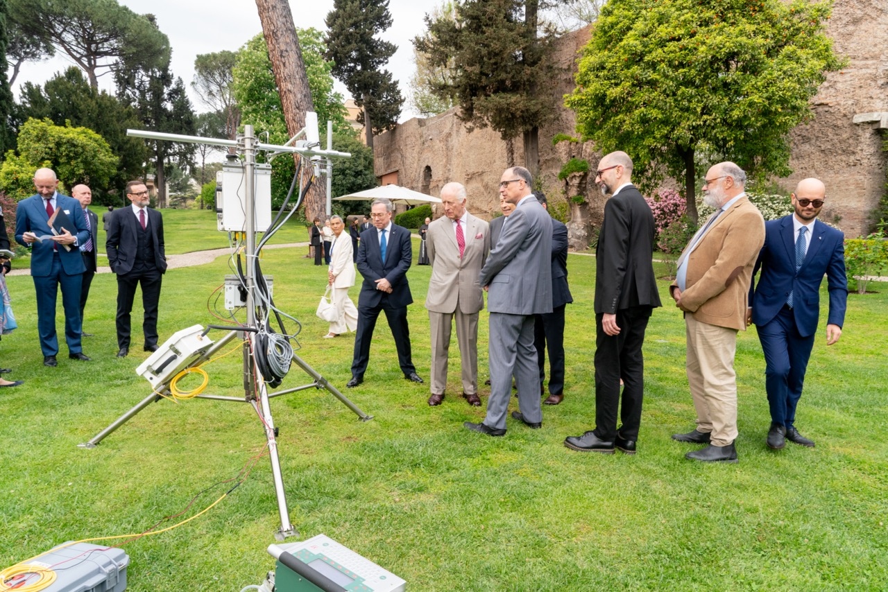 group of people standing around an eddycovariance instrument on green grass 