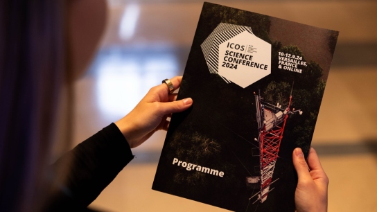 person holding a printed brochure of ICOS Science Conference